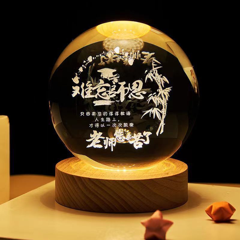 Decorative glass ball with Chinese text and bamboo design on a wooden base