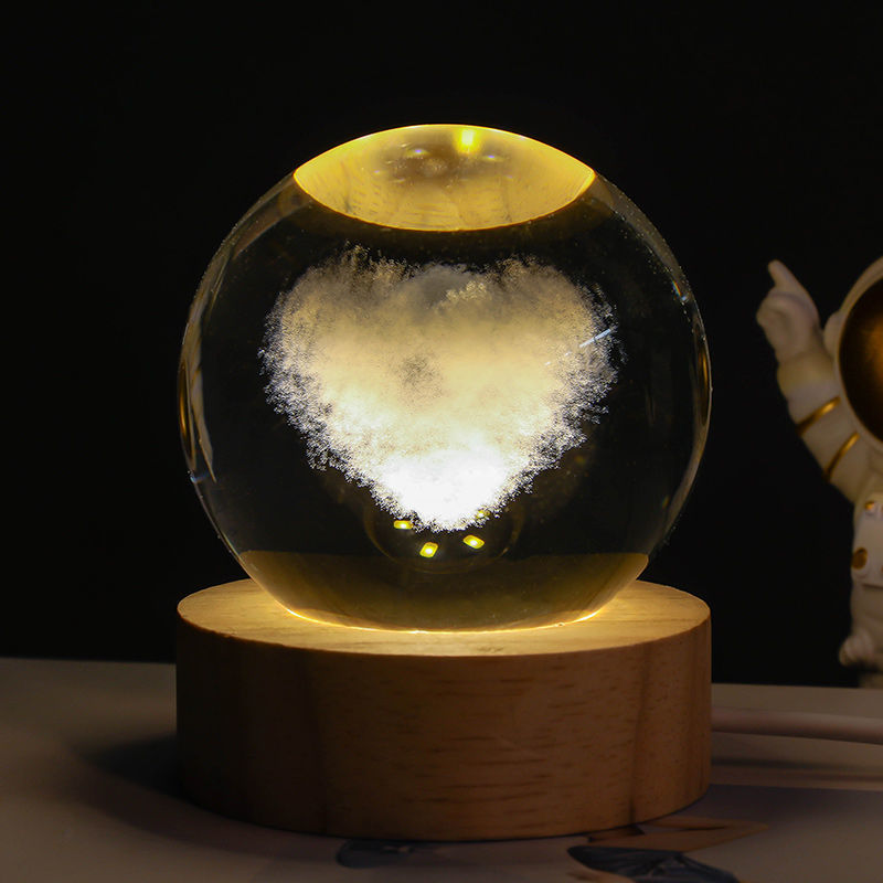 Glass sphere with a glowing heart on a wooden base against a dark background