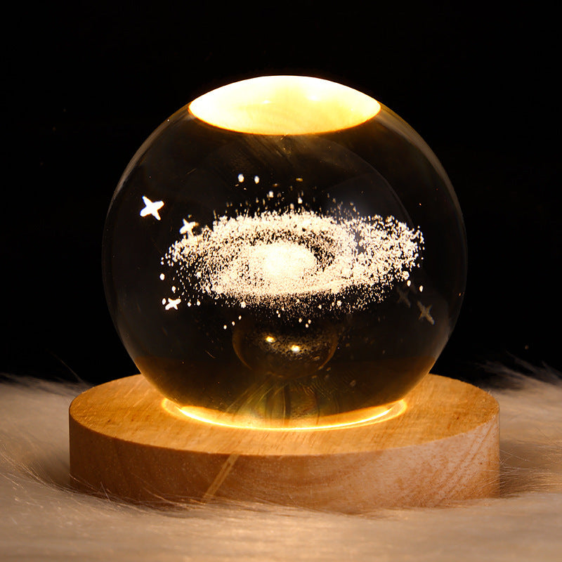 Glass sphere with galaxy design on a wooden base against a dark background