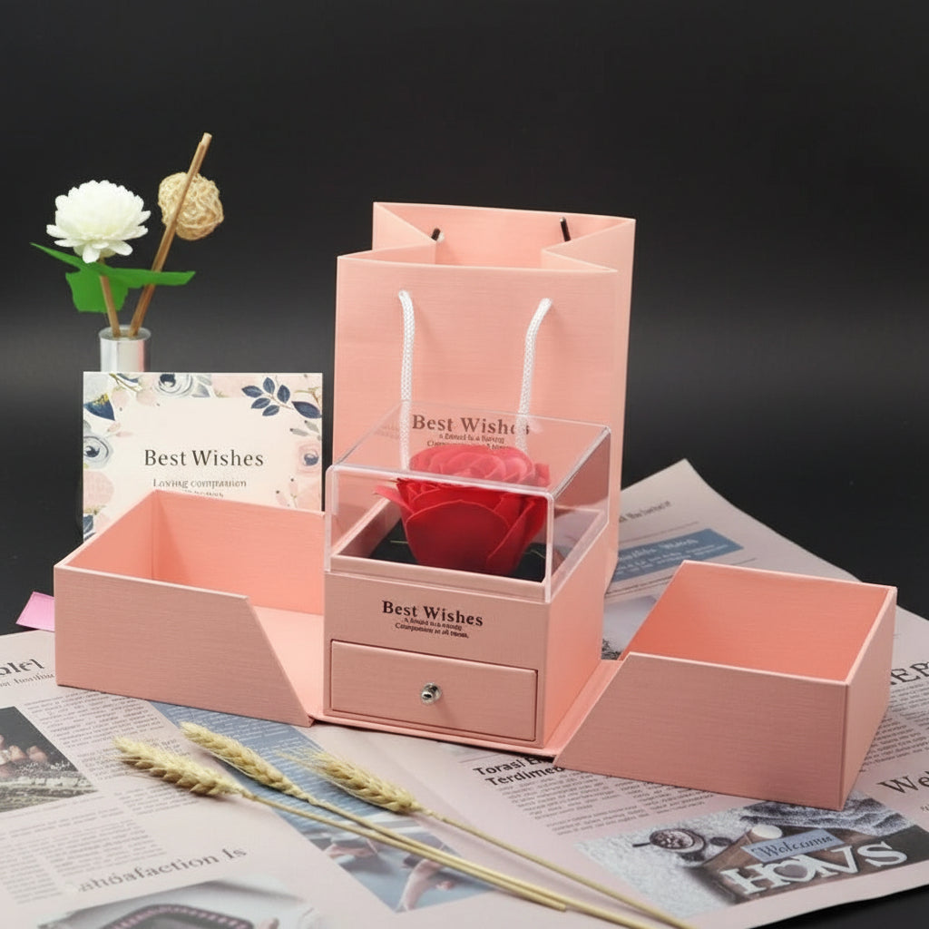 Pink jewelry box with heart-shaped object and 'Best Wishes' card on a newspaper background