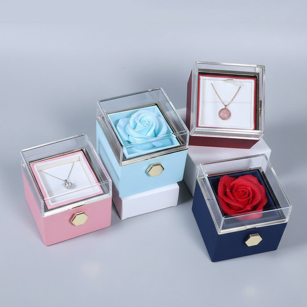 Four decorative boxes with flowers and necklaces on a reflective surface