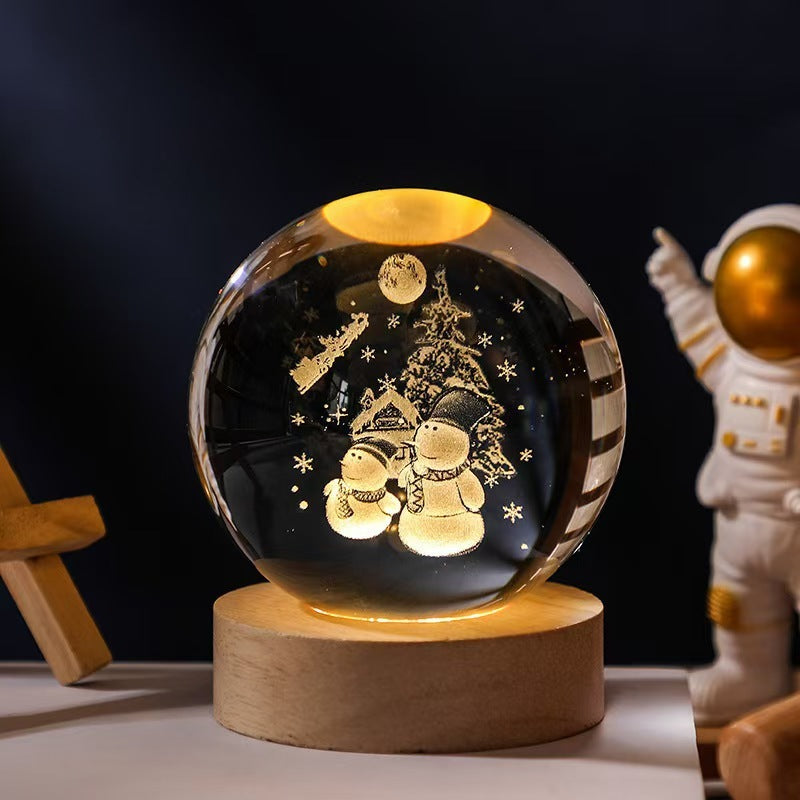 Decorative crystal ball with snowmen and a tree inside, on a wooden base with an astronaut figure in the background.