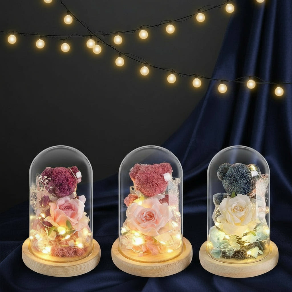 Three glass dome lights with teddy bears and flowers, string lights in the background.